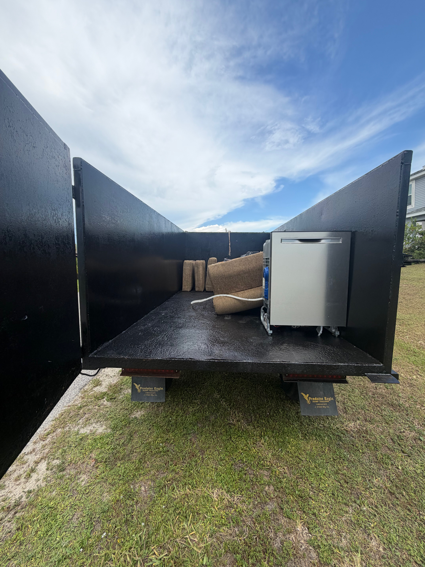 Open dump trailer with couch cushions and dishwasher ready for haul away